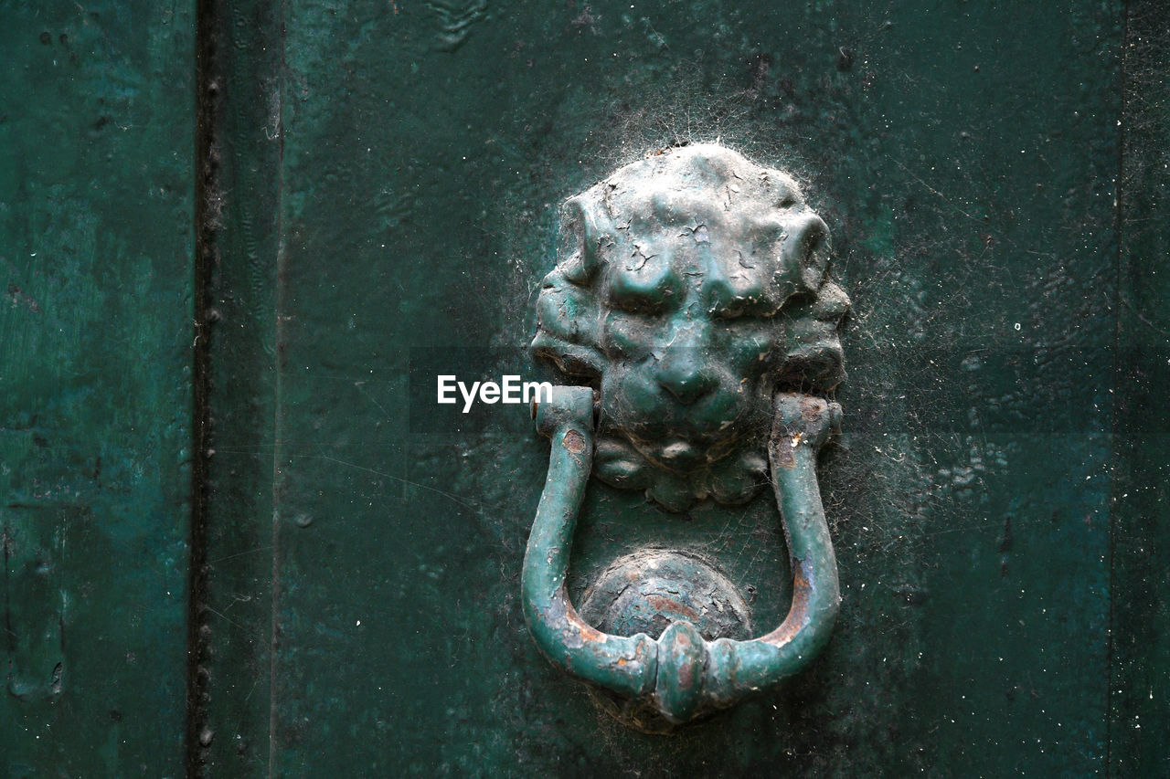 CLOSE-UP OF OLD DOOR KNOCKER ON METAL GATE