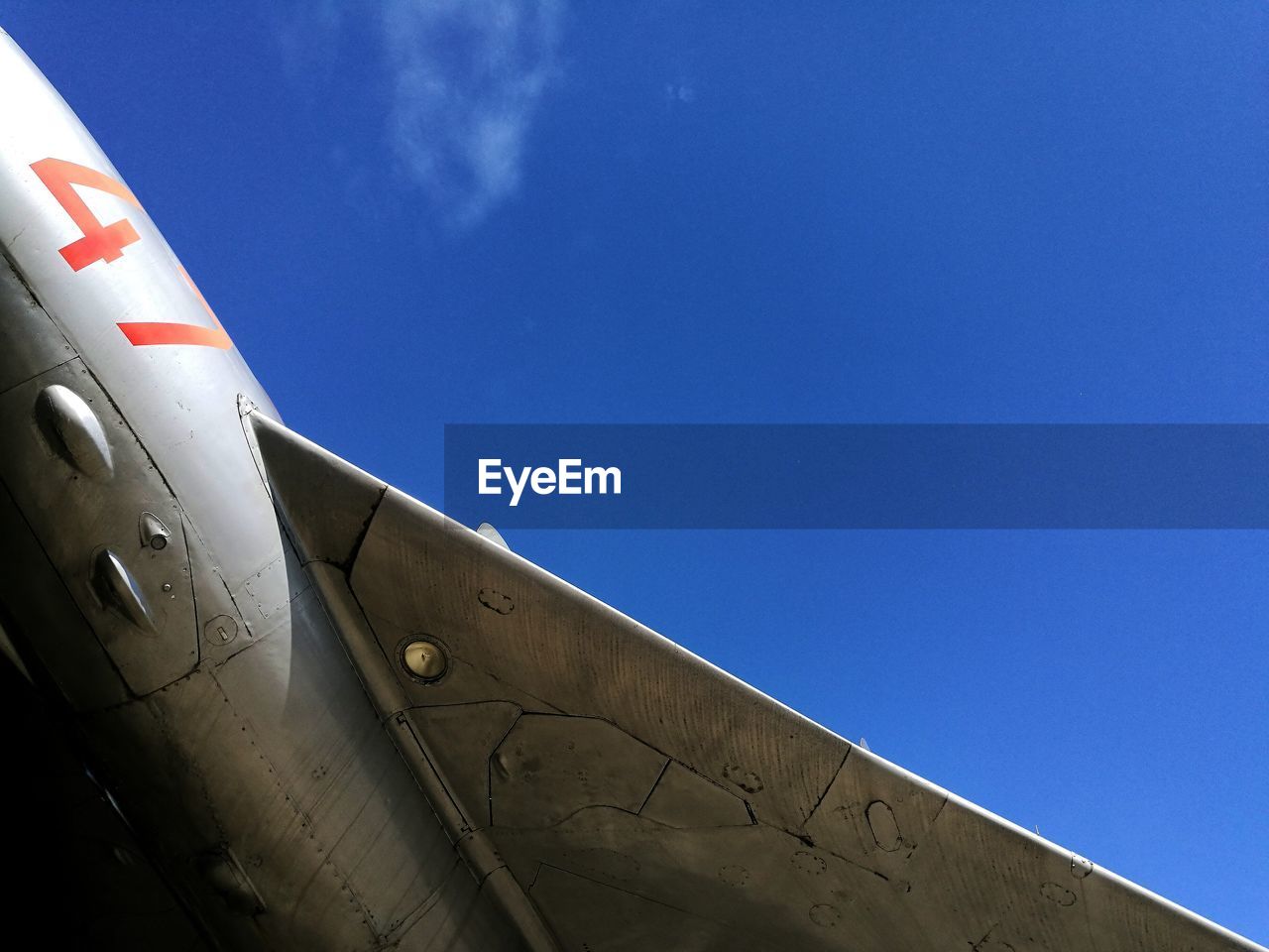 Low angle view of airplane wing against blue sky