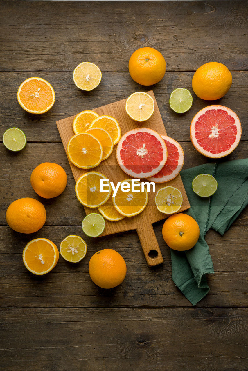 Fresh juicy vitamin oranges, grapefruits, limes, lemons on board. food background. vertical top view