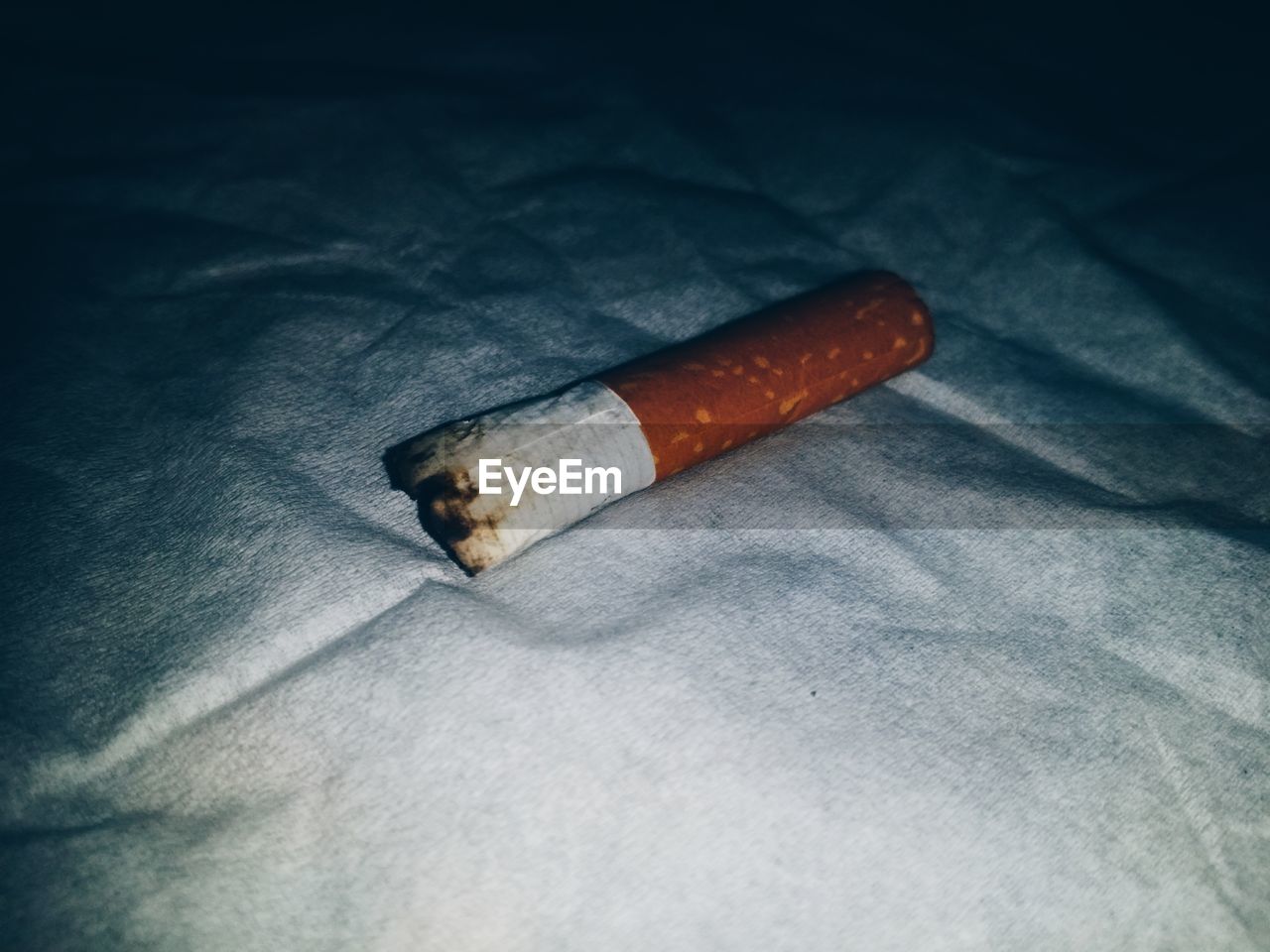 Close-up of cigarette butt on fabric