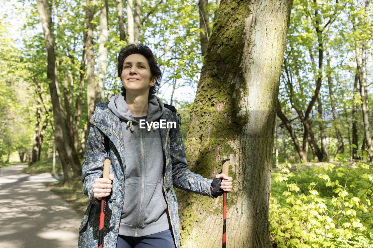 Portrait woman trekking with sticks, happy caucasian 36 yo hiking female, nordic walking with sticks