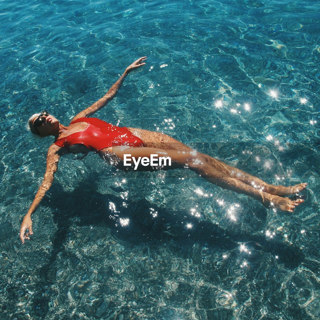 High angle view of woman in sunglasses relaxing in water