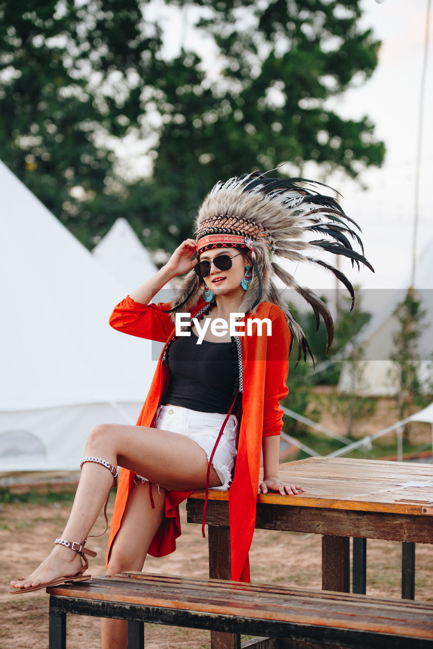 Portrait of young woman wearing headdress while sitting on picnic table