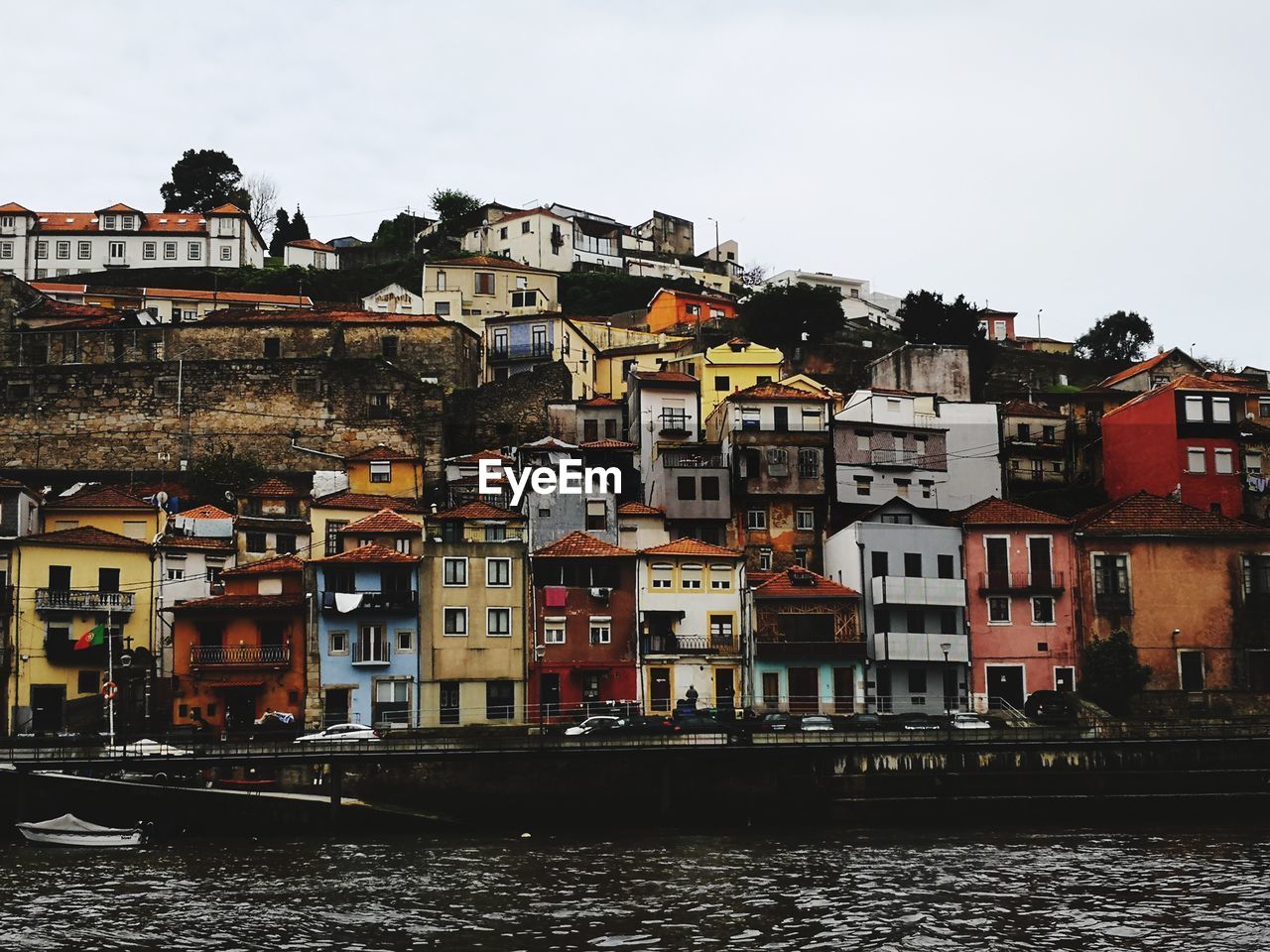 Residential buildings by river against sky