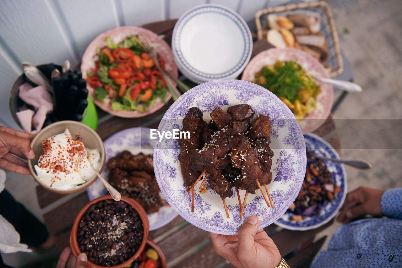 High angle view of man's hand holding cooked meat at buffet during party