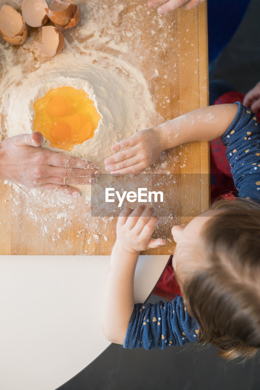 Children preparing dough while standing together at kitchen table with flour