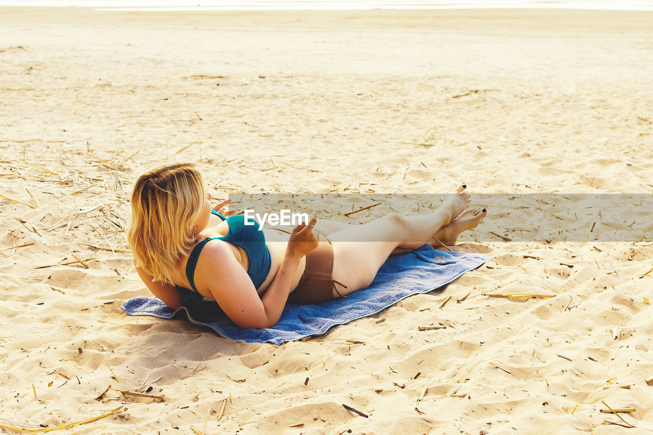 Young girl sunbathing on a wild beach by the sea