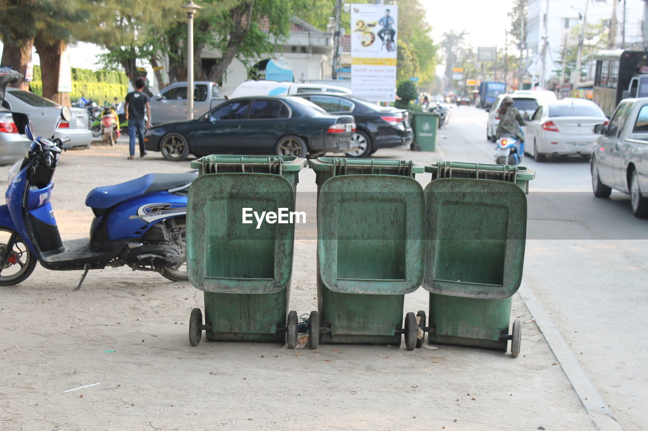 Garbage bins in parking lot by road at city