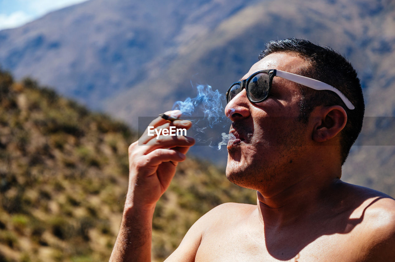 Portrait of man drinking water from sunglasses