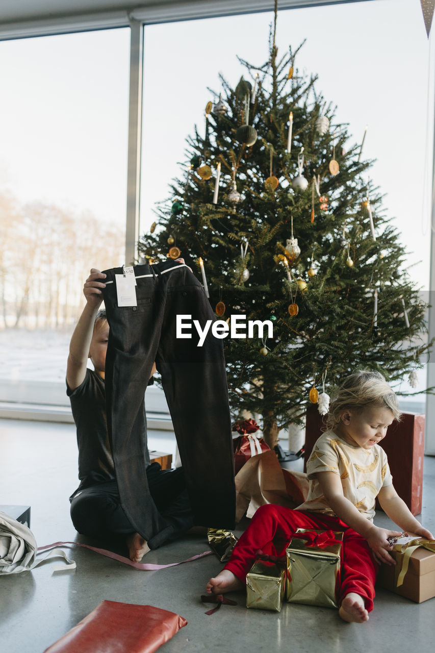 Brother and sister opening christmas presents under christmas tree