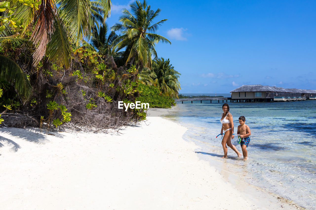 Mother and son getting out of the water on a beach in the maldives