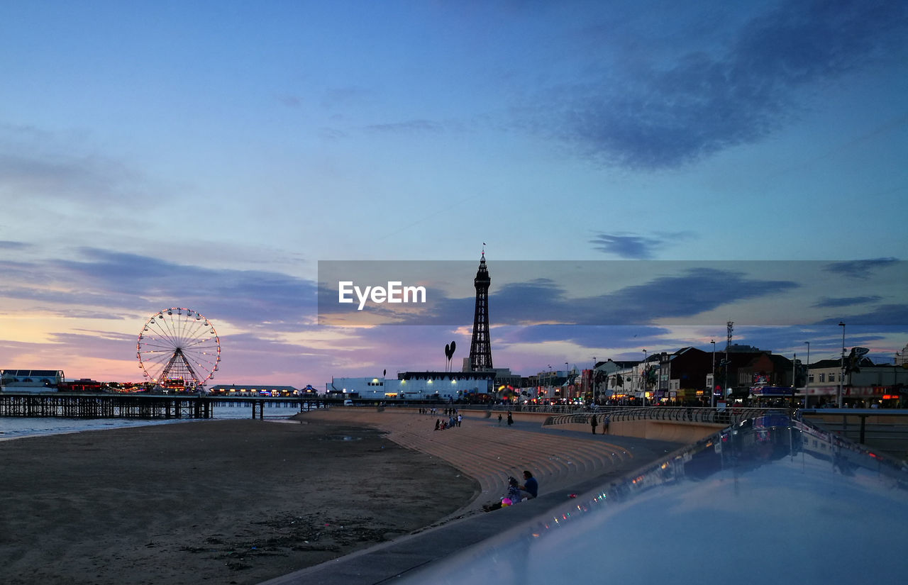 Amusement park by beach against sky during sunset in blackpool