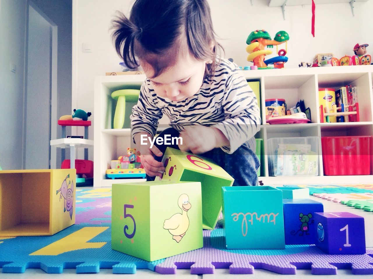 Toddler girl playing with toy blocks at home