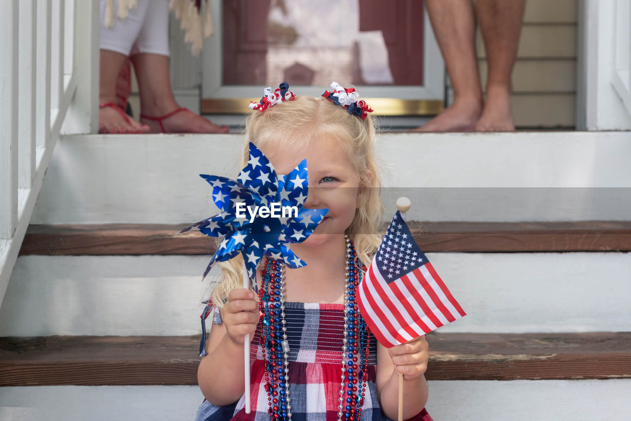 Portrait of smiling girl holding american flag on steps