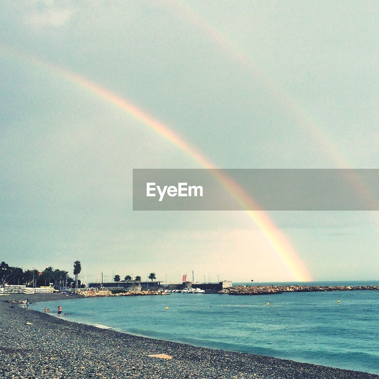 Scenic view of beach against rainbow