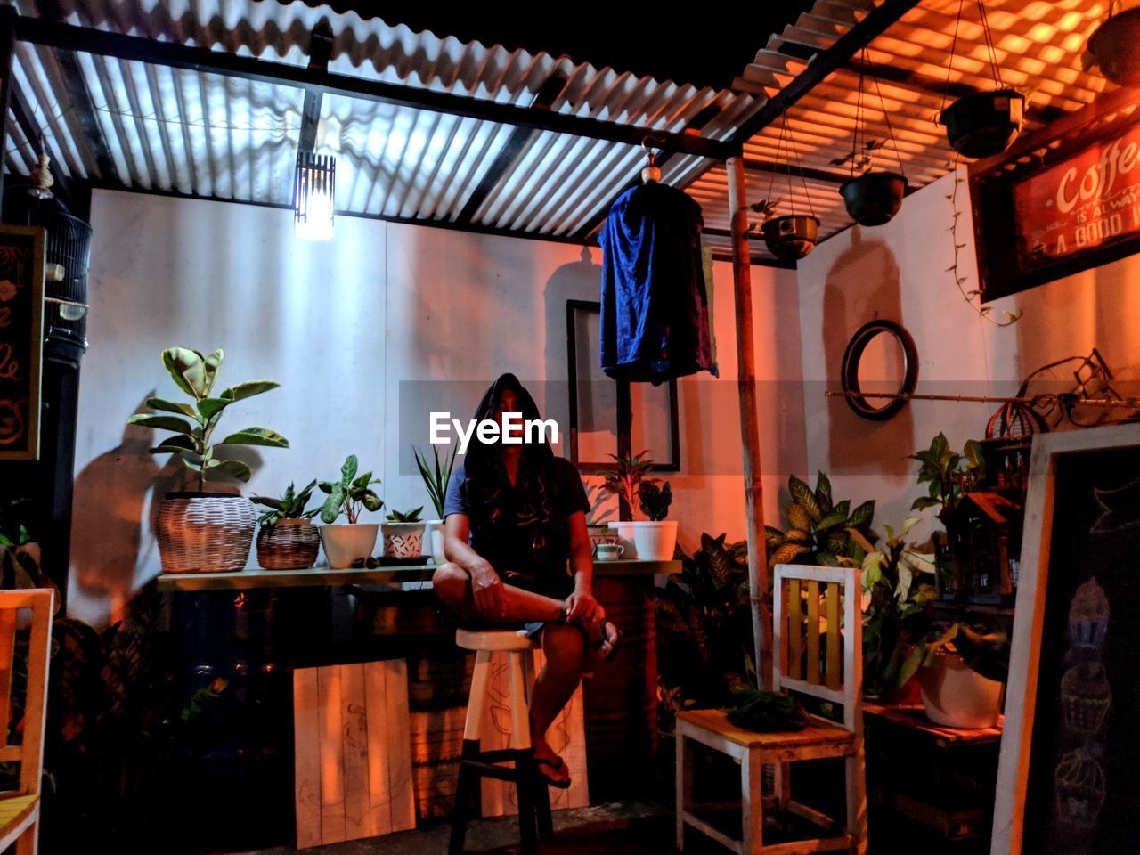 YOUNG WOMAN SITTING ON CHAIR IN CAFE