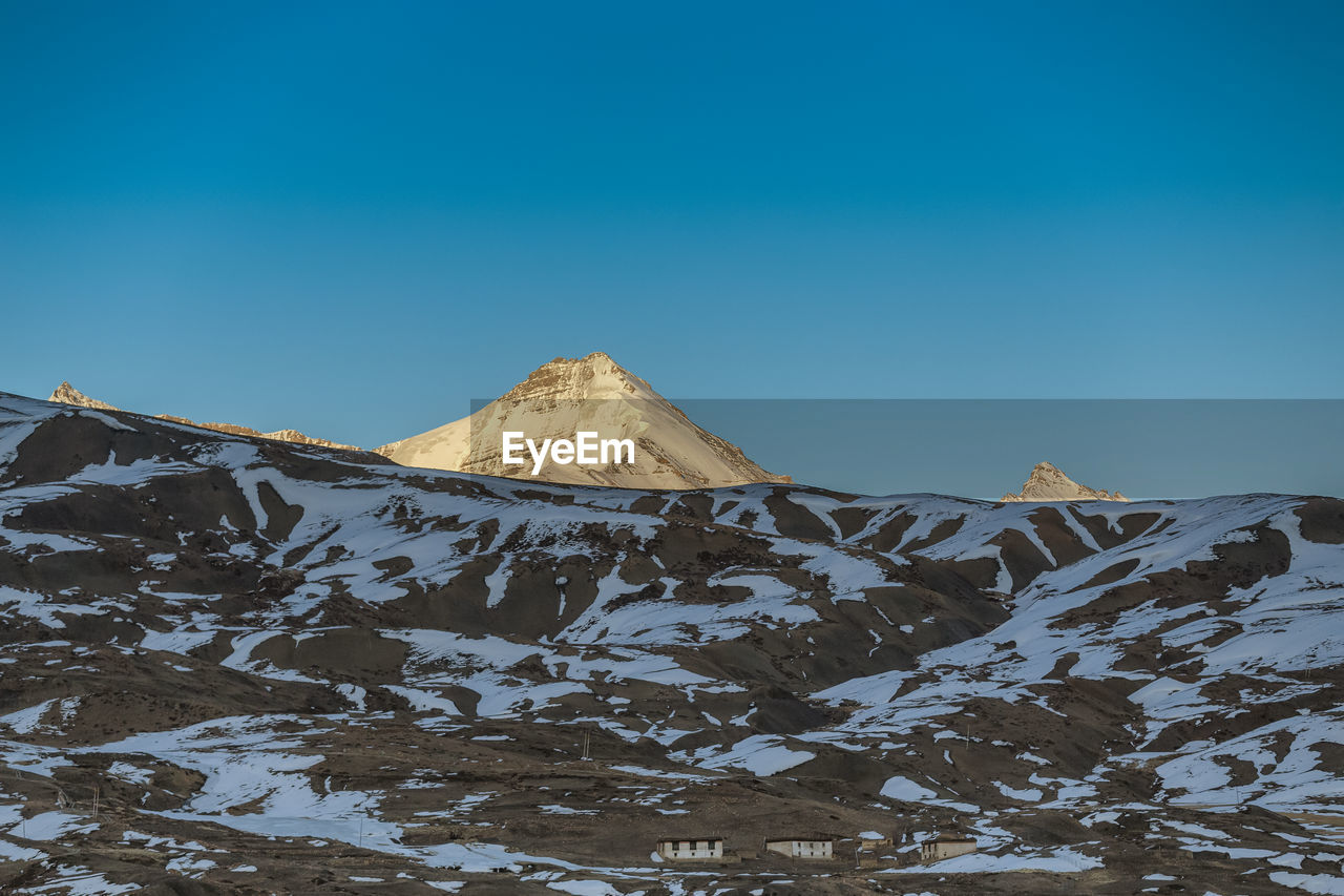 Scenic view of snowcapped mountains against clear blue sky