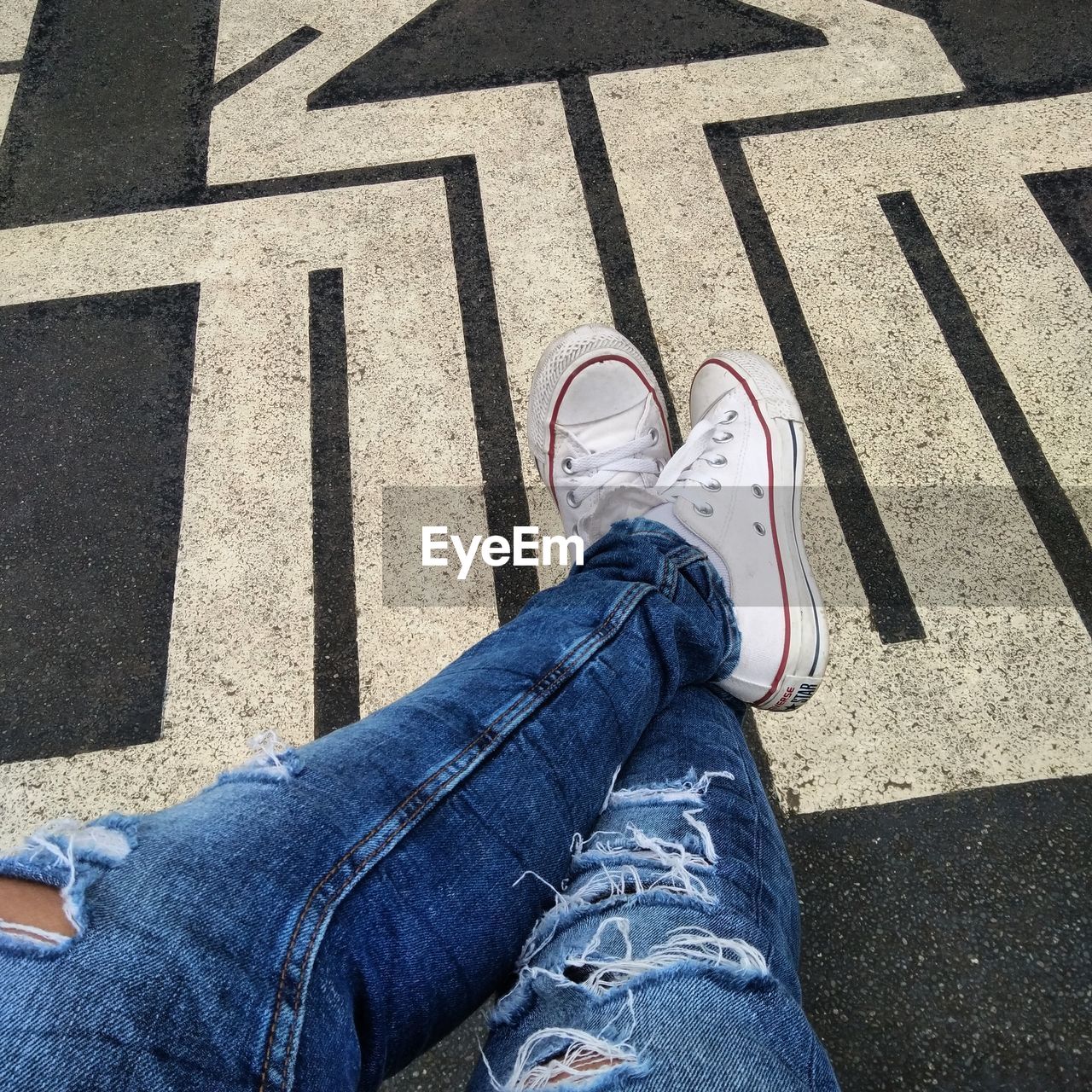 Low section of person sitting at footpath