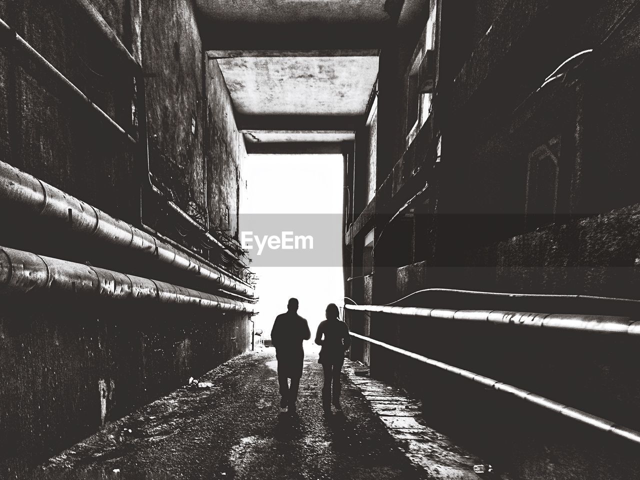 Rear view of silhouette people walking in tunnel