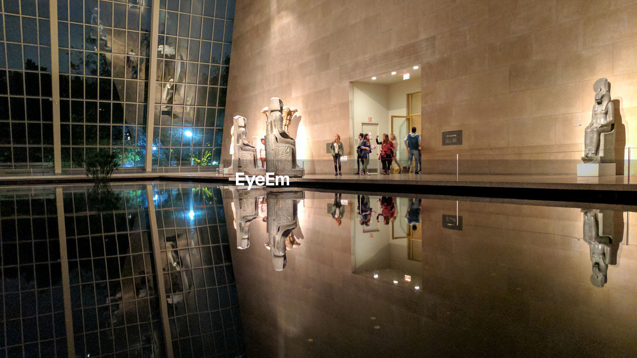 GROUP OF PEOPLE WALKING IN ILLUMINATED BUILDING