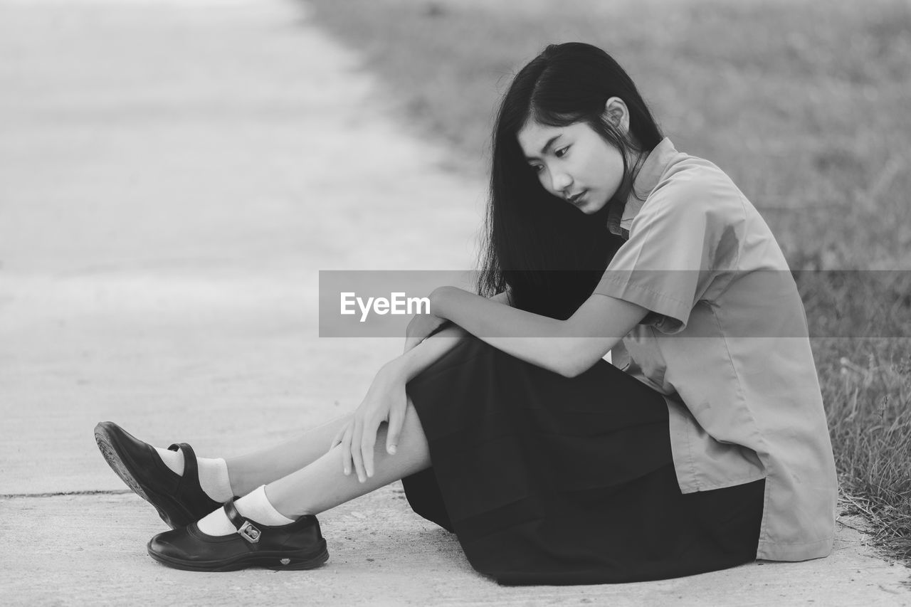 SIDE VIEW OF YOUNG WOMAN SITTING ON SEAT