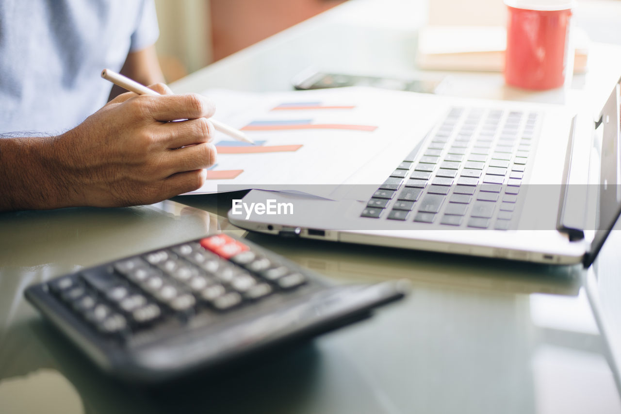 Cropped image of man using laptop on table