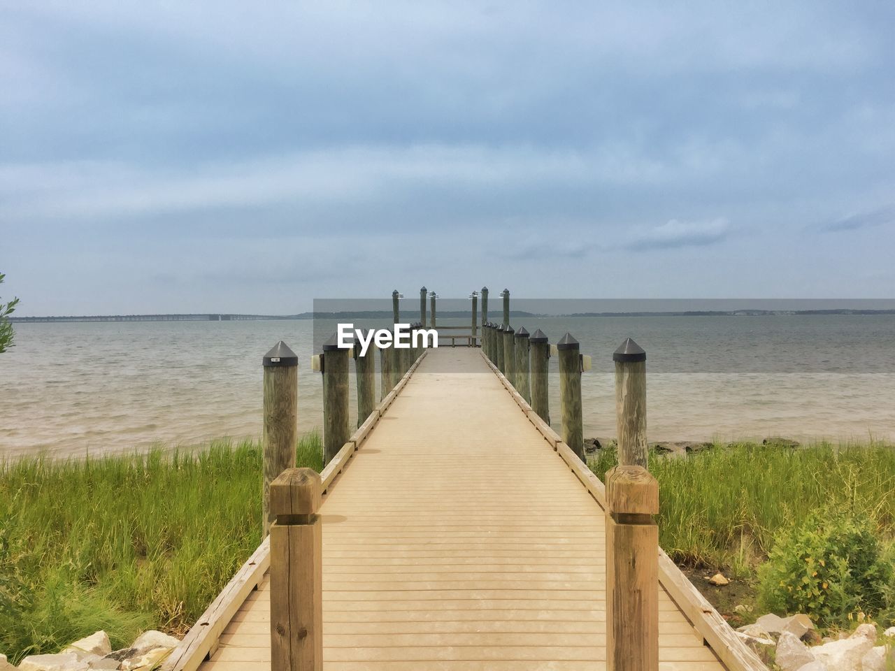 Pier over sea against cloudy sky