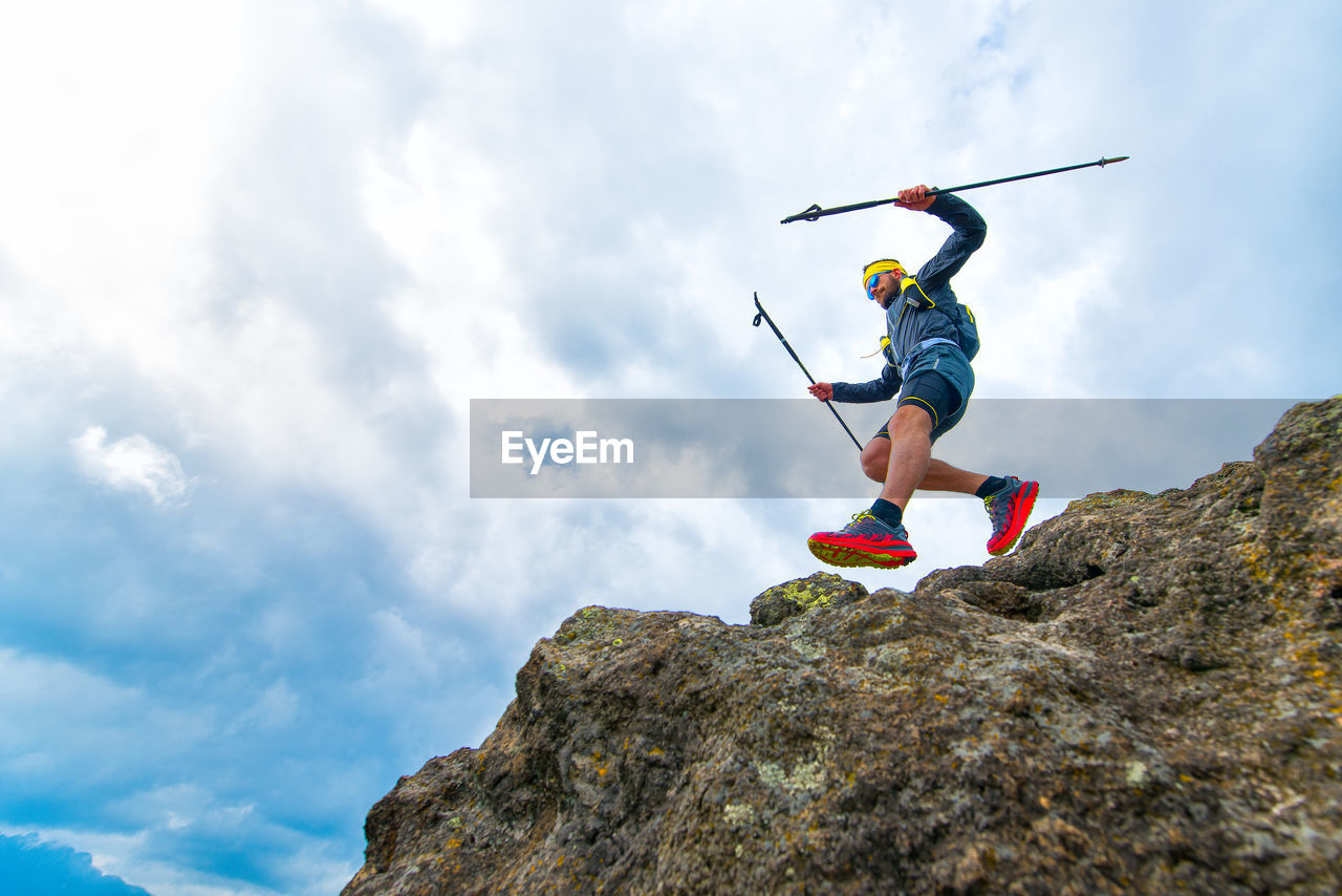 Male athlete falls over a cliff with sticks while practical training at the mountain trail