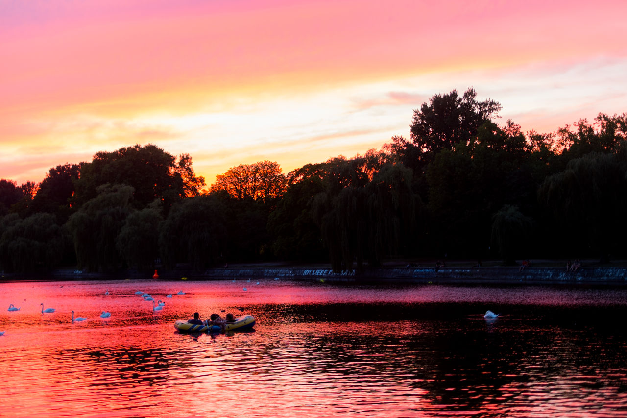 People canoeing in lake during sunset
