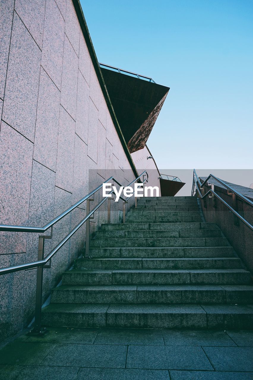 Low angle view of staircase by building against clear blue sky