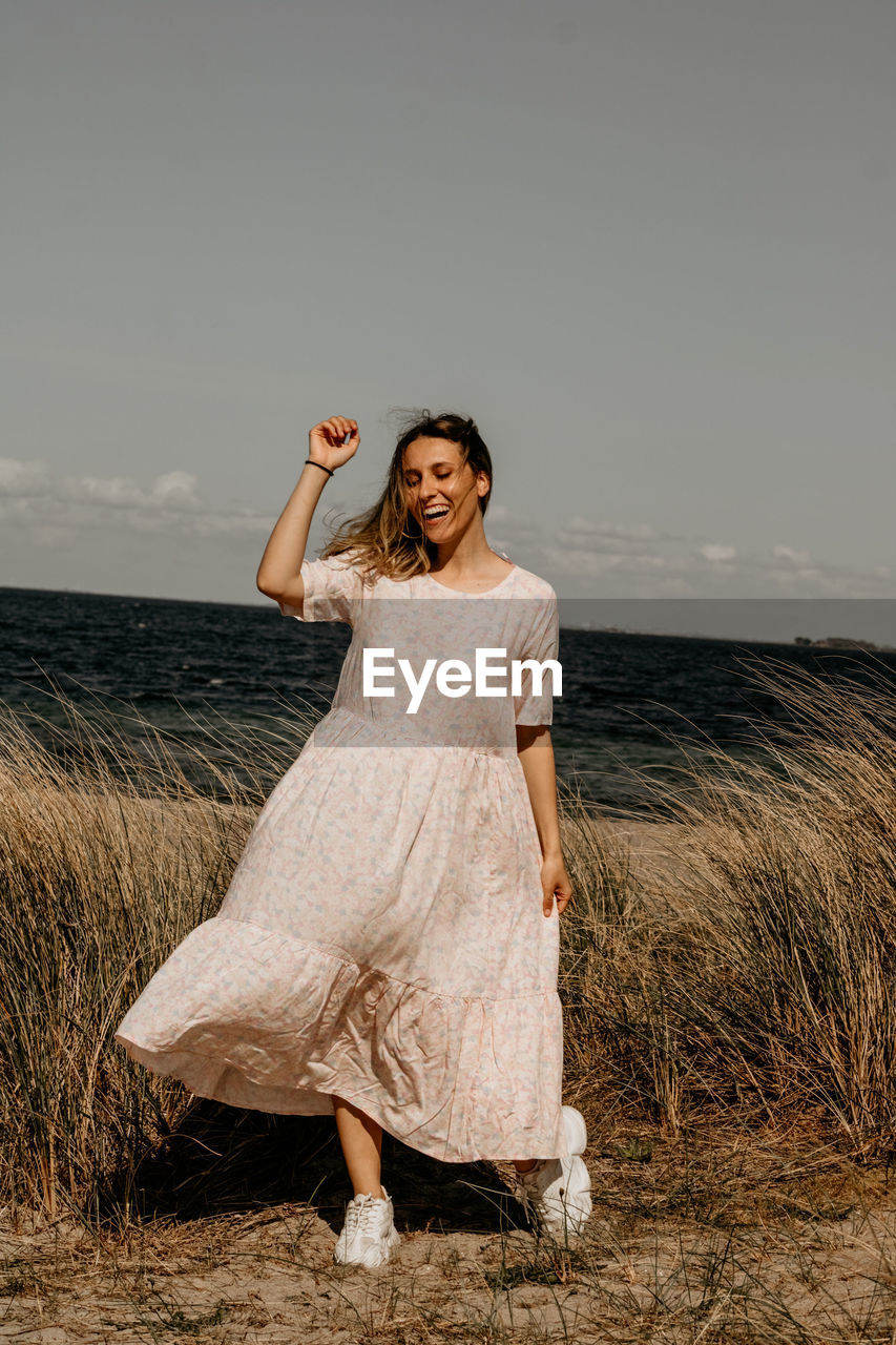 Portrait of young woman standing at beach