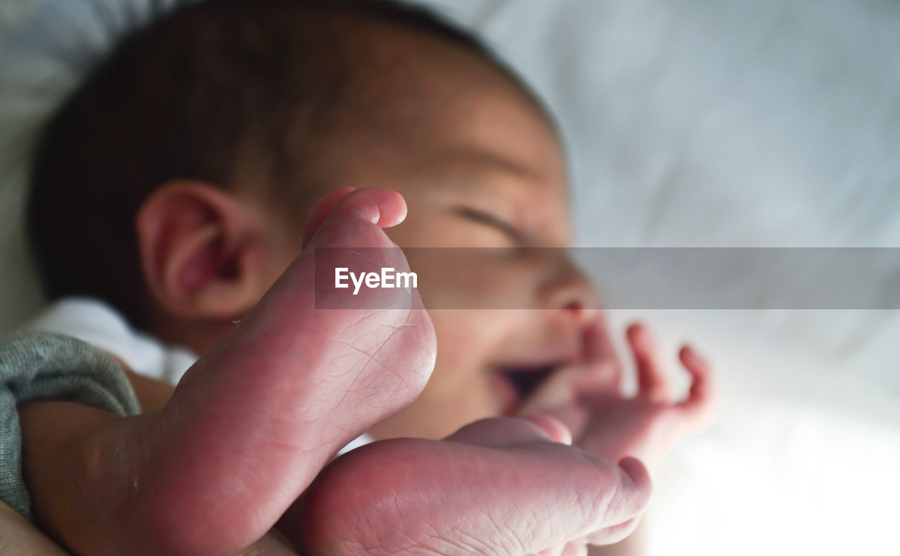 Close-up of newborn baby sleeping on bed