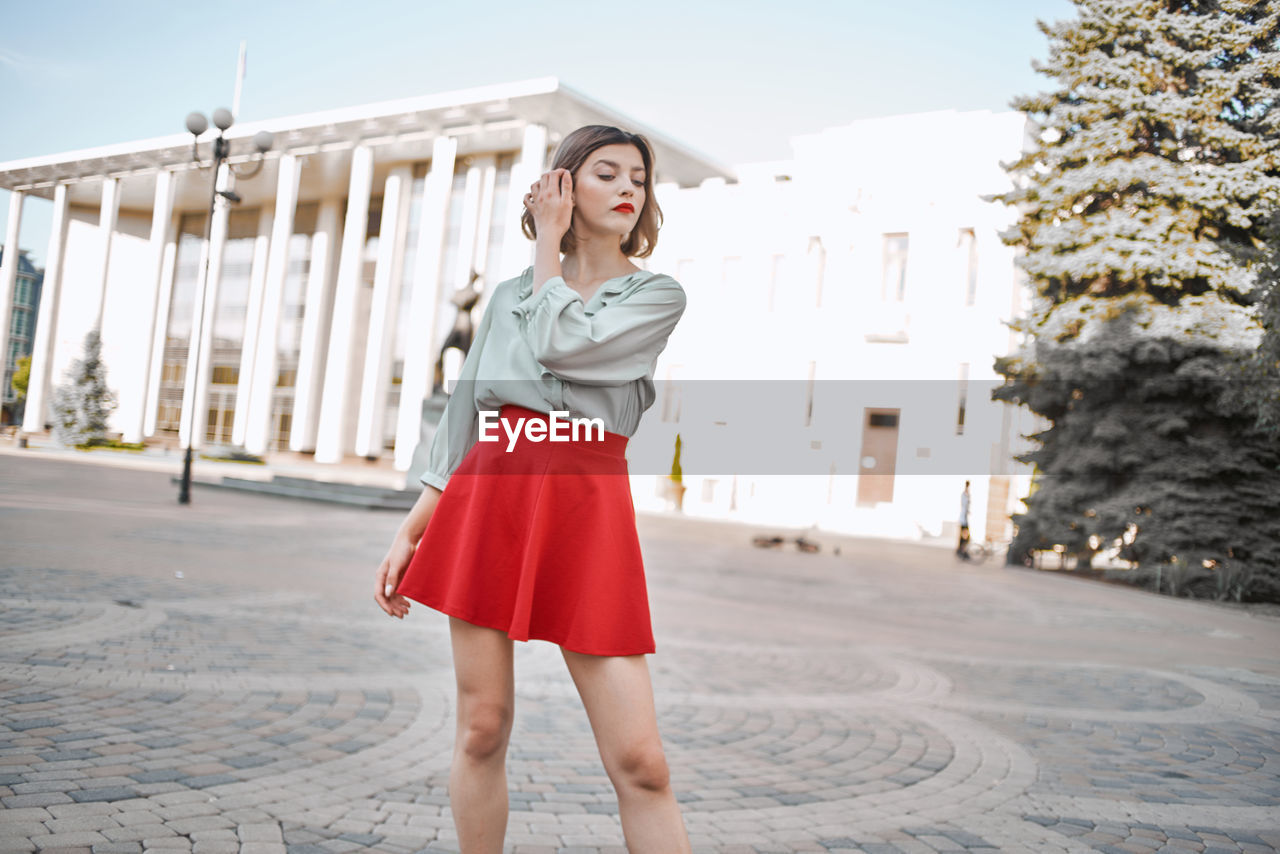 Full length of young woman standing against built structure