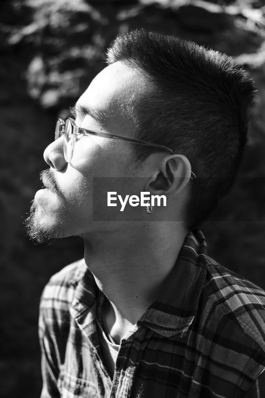 Close-up of young man wearing eyeglasses looking away