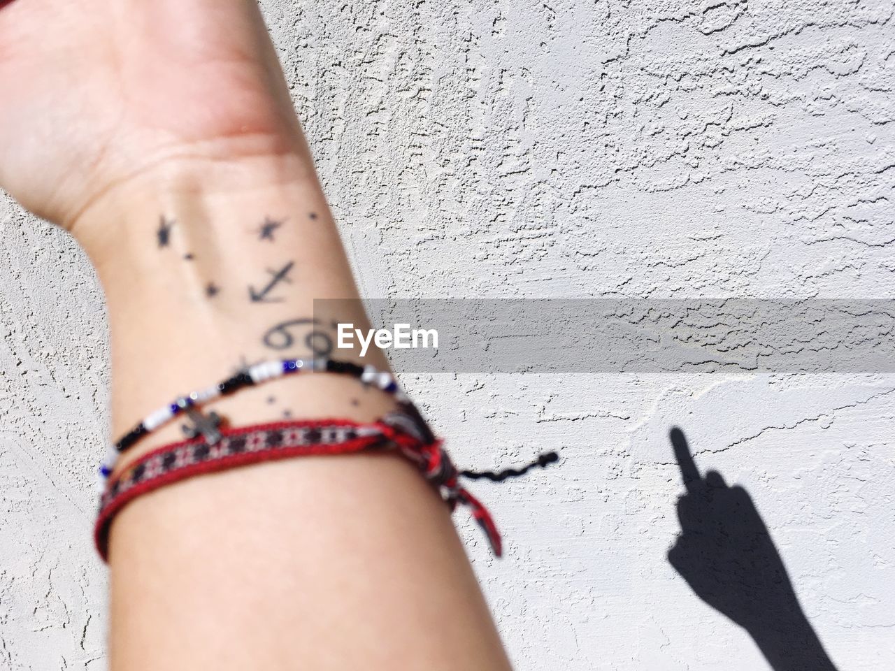Cropped hand of woman wearing bracelet against wall