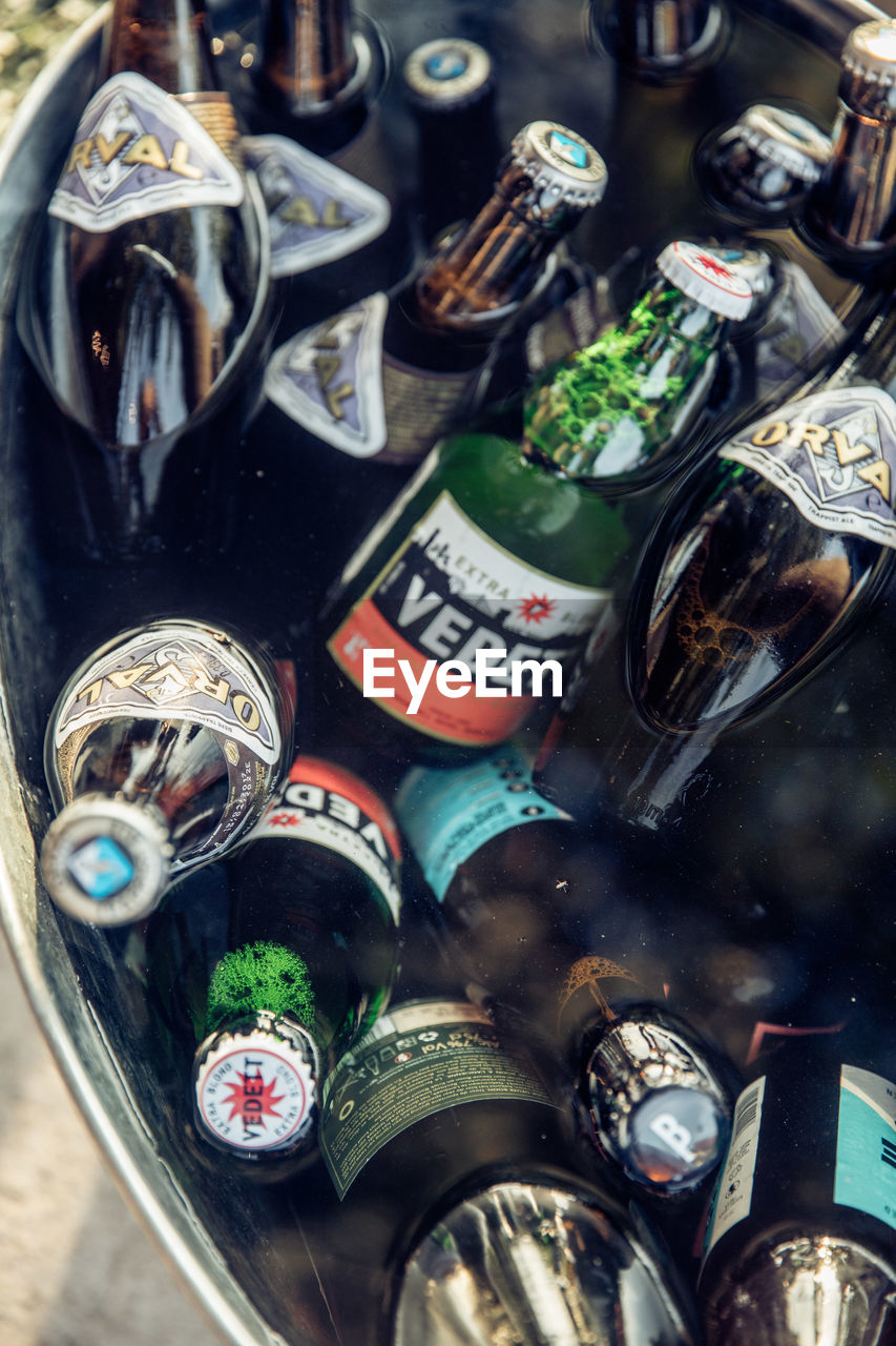 HIGH ANGLE VIEW OF WINE BOTTLES IN GLASS ON TABLE