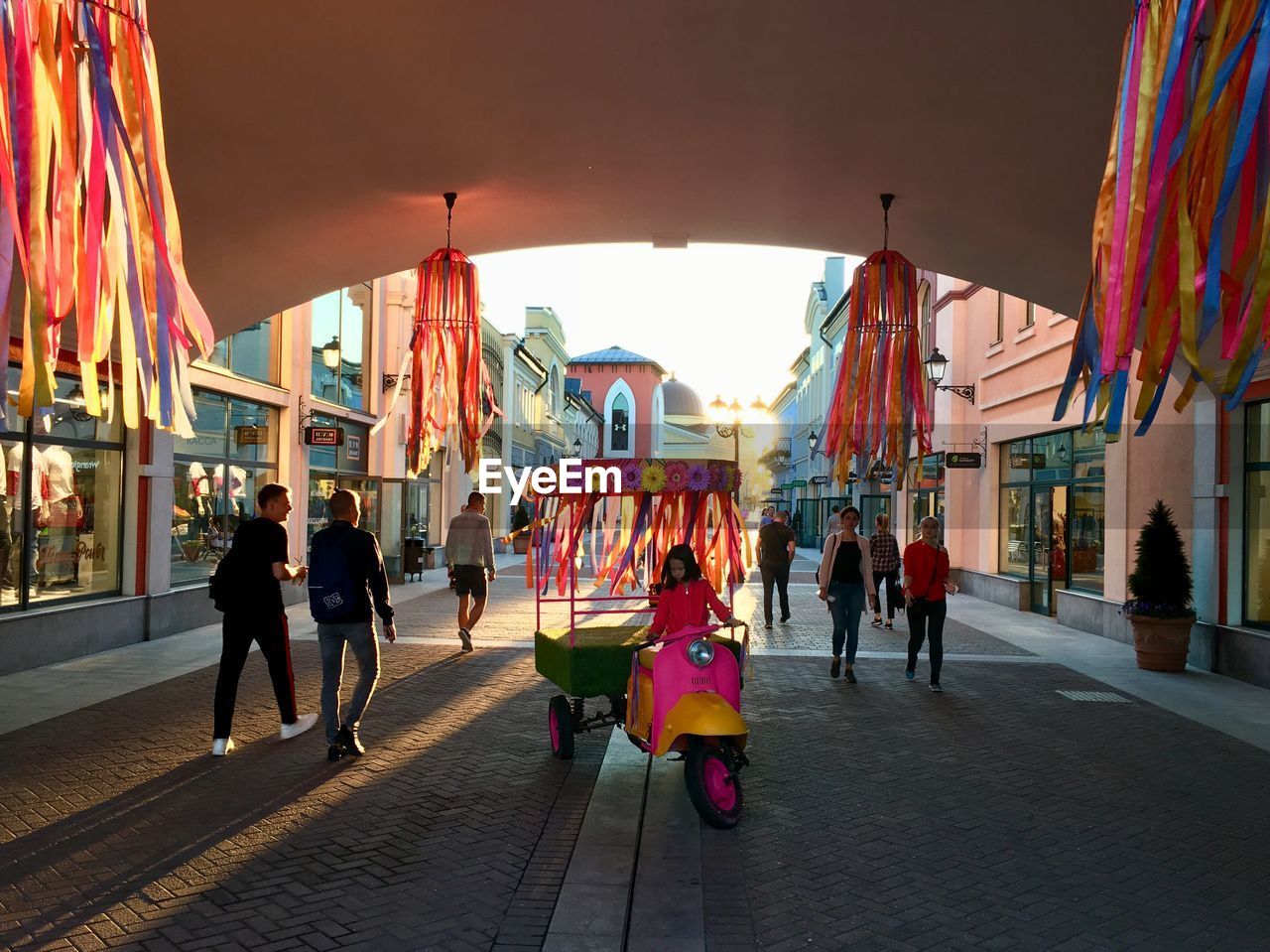 PEOPLE WALKING ON STREET IN CITY AT DUSK