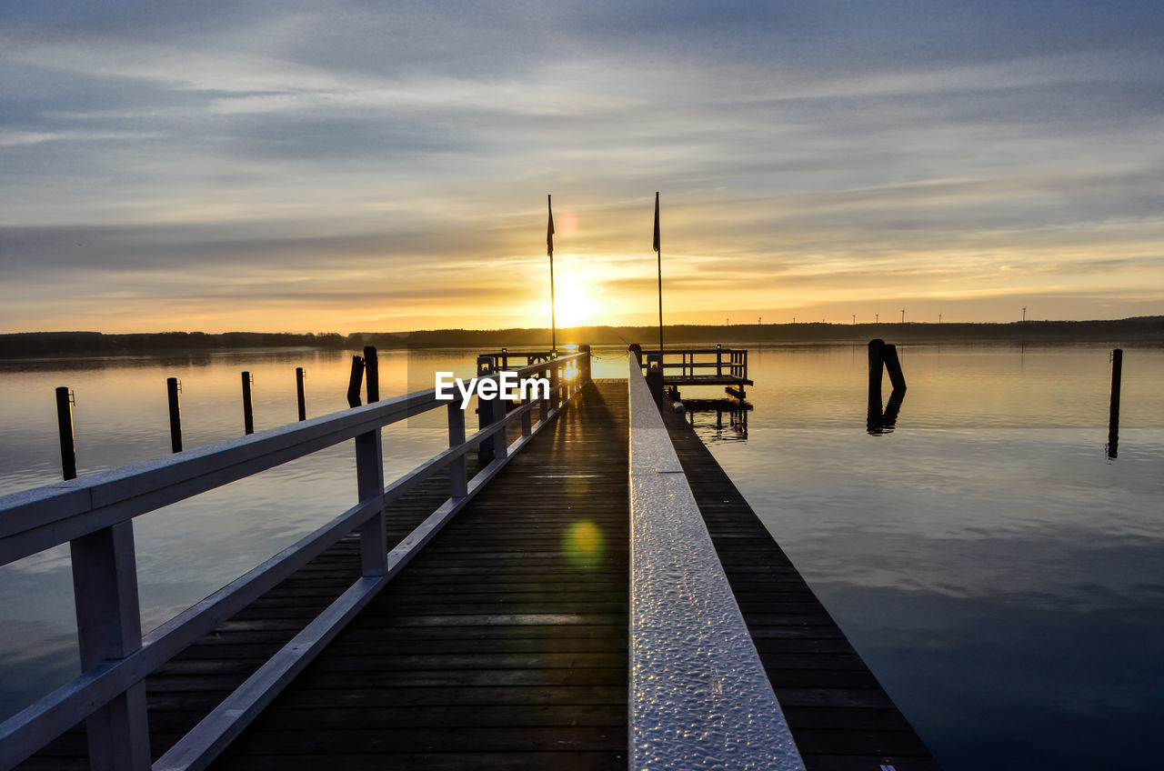 Pier over sea against sky during sunset