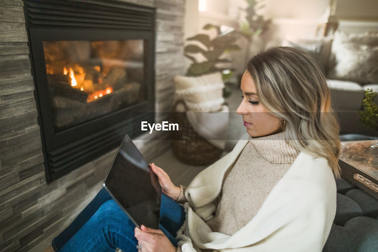 High angle view of woman using digital tablet while sitting on sofa at home