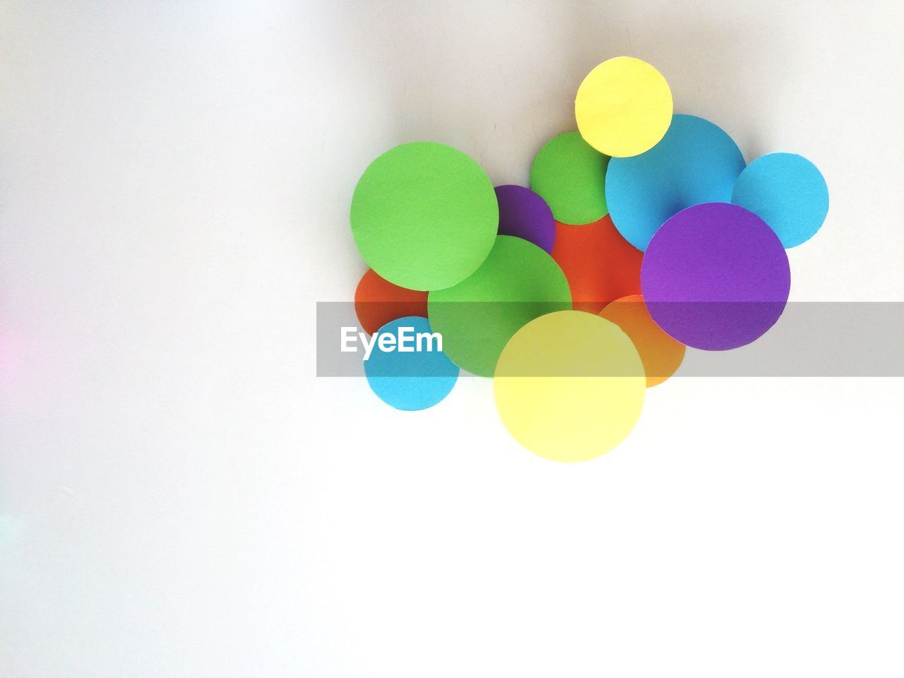 Colorful circle shape paper designs on white wall at home