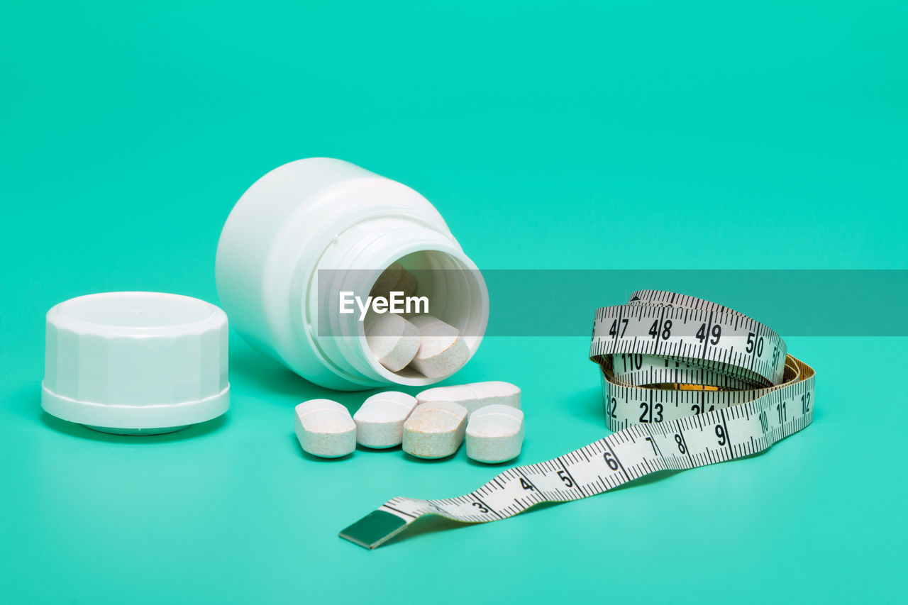 Close-up of pills and tape measure on green background