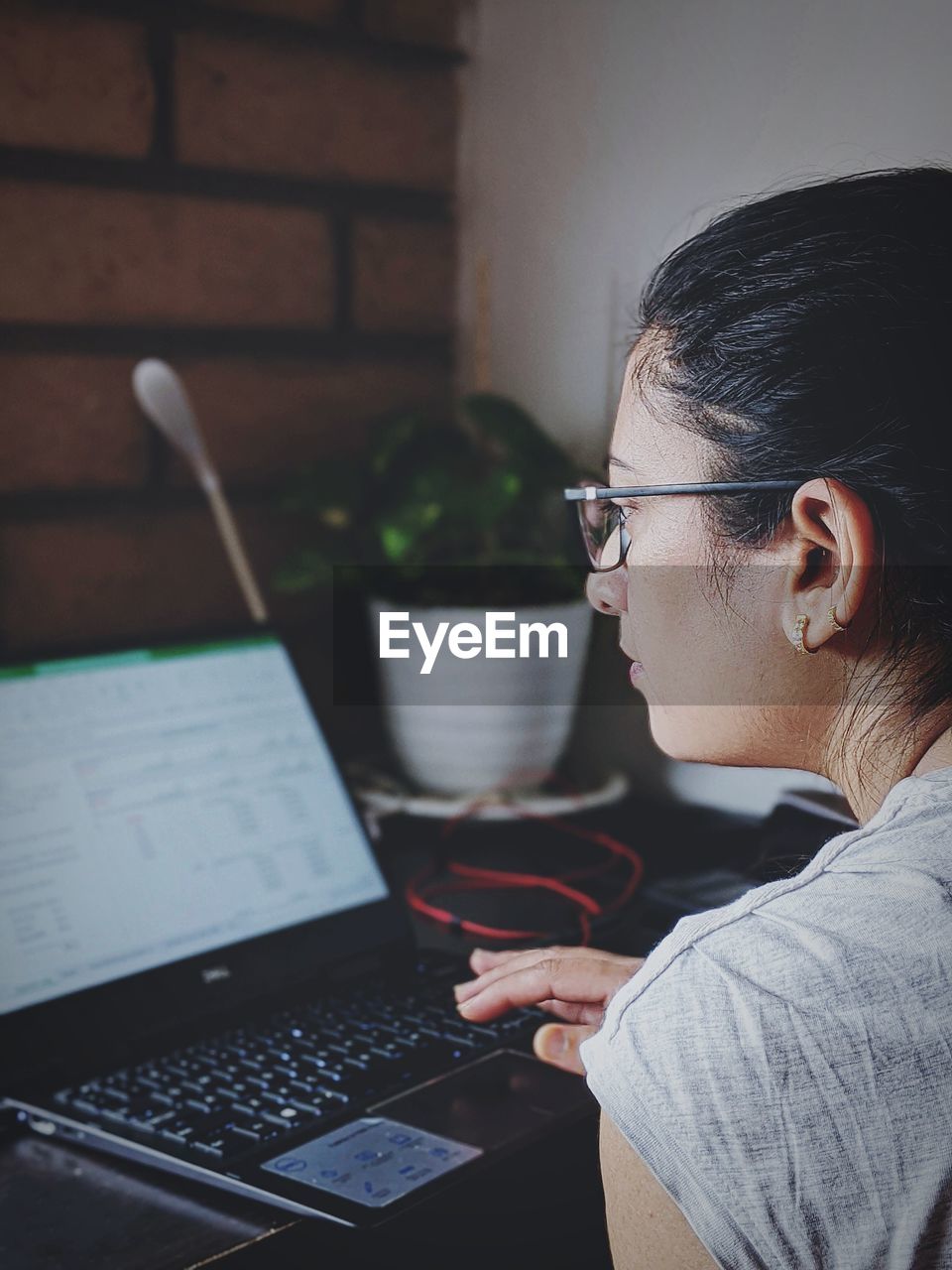 Woman using laptop while sitting on table during pandemic. working online