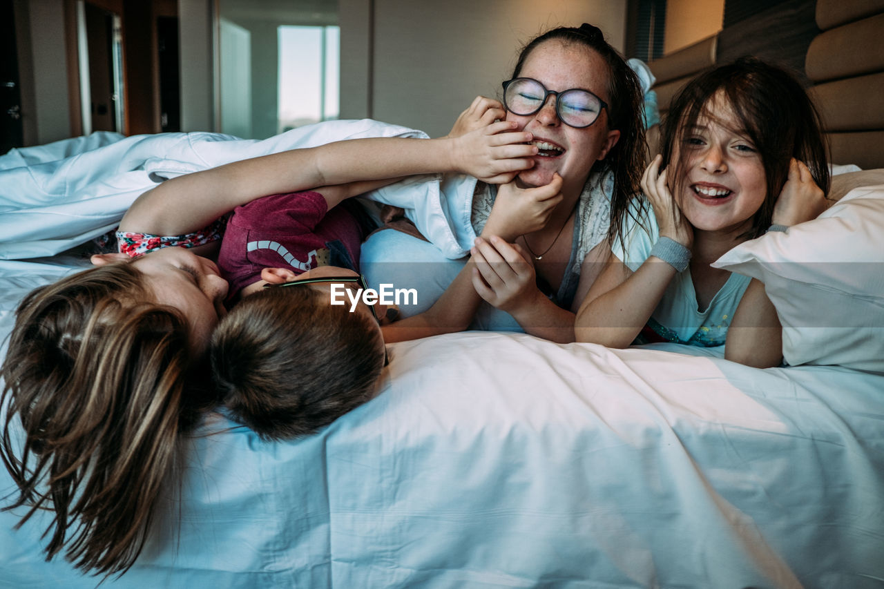 Young kids playing on hotel bed while on vacation