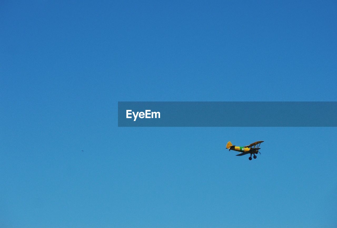 Low angle view of airplane flying against clear blue sky