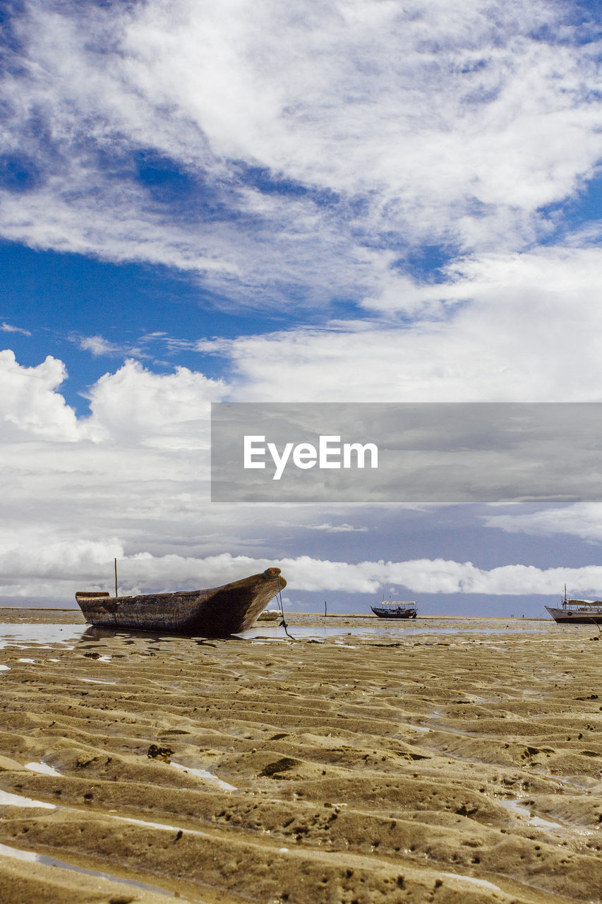 Boat moored on beach against sky