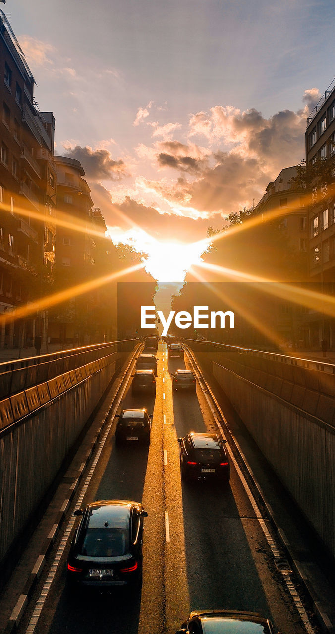 Cars on road in city against sky during sunrise 