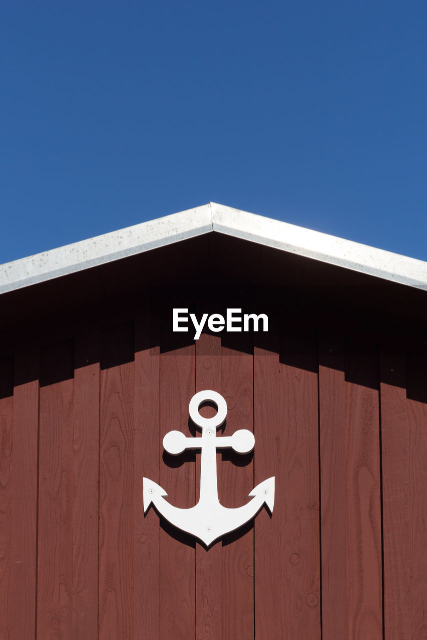 Low angle view of building  with an anchor against blue sky