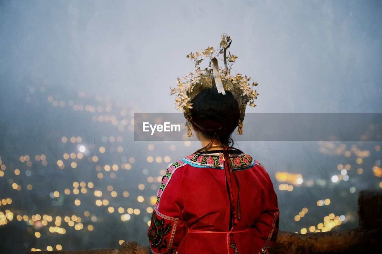 Rear view of young woman in traditional clothing standing against sky