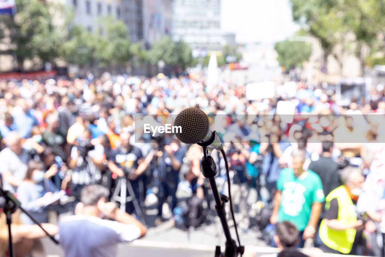 Focus on microphone, blurred group of people at mass protest