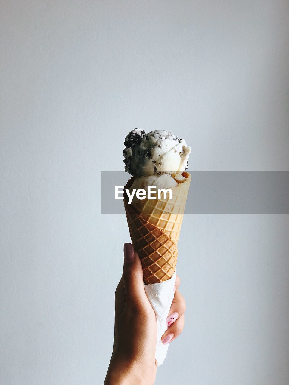 MIDSECTION OF ICE CREAM CONE AGAINST WHITE BACKGROUND